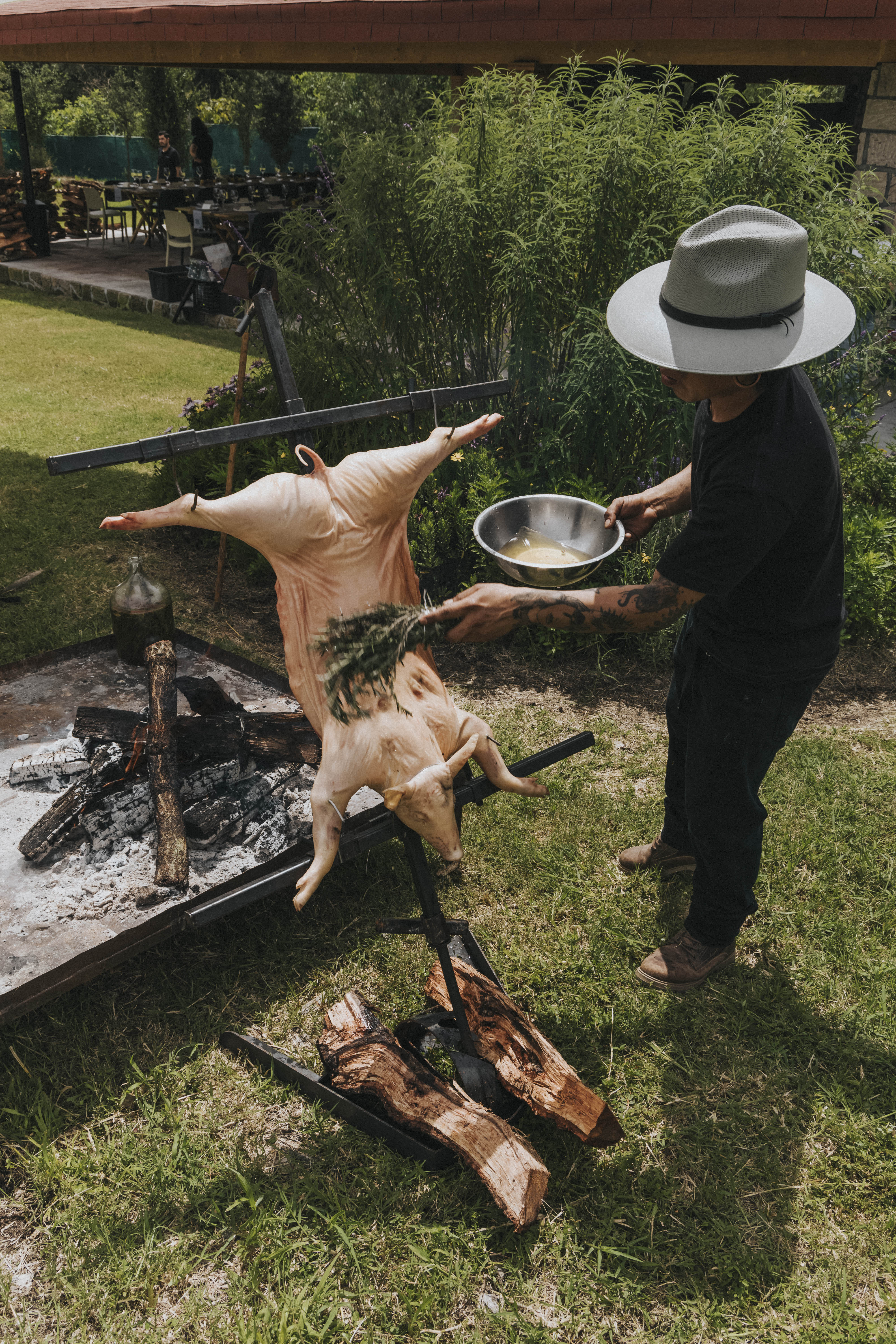 Asador Cruz en uso cocinando un lechón junto al fuego